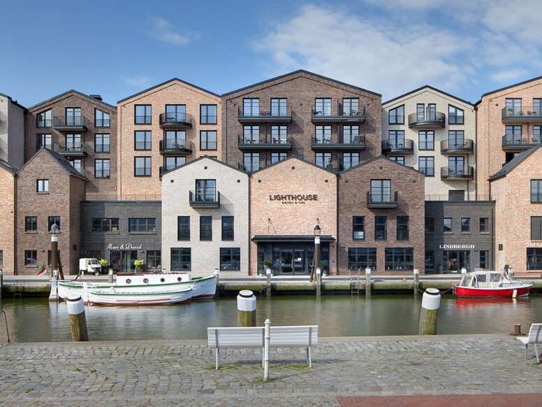 Lighthouse Hotel & Spa in Büsum Harbour basin with boats; on the opposite side of the shore are modern brick houses